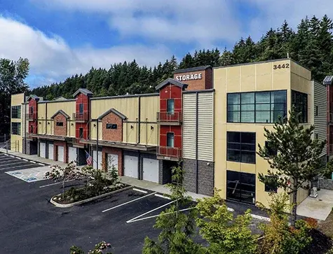 Multi-story self storage building with upper-level units, modern exterior design, and drive-up access bays surrounded by trees.
